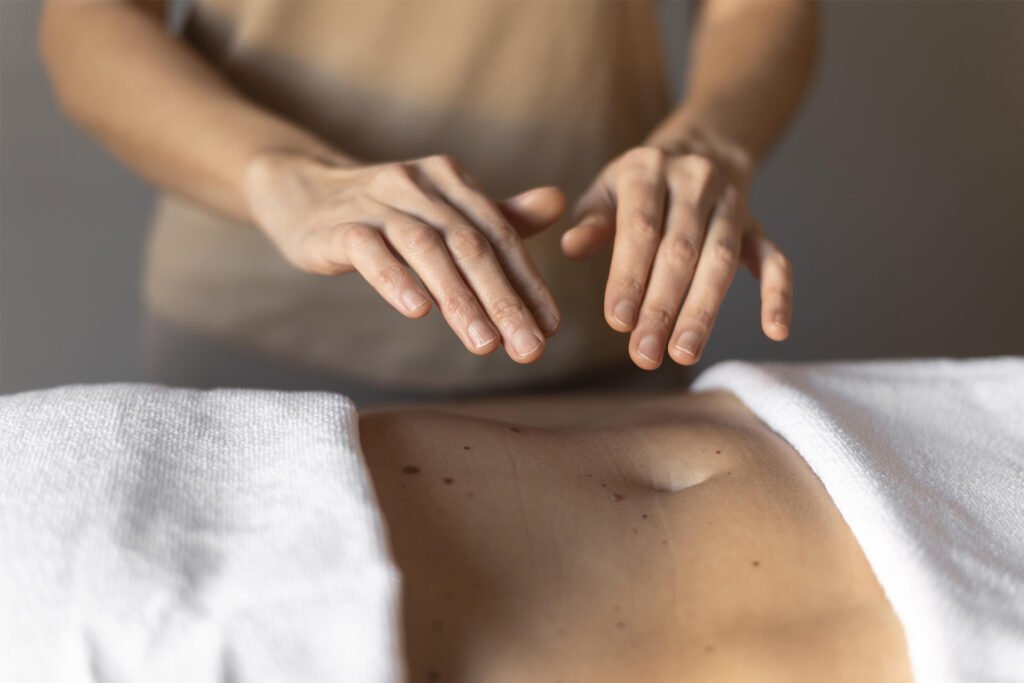 Mans de terapeuta fent Reiki sobre l'abdomen d'una dona