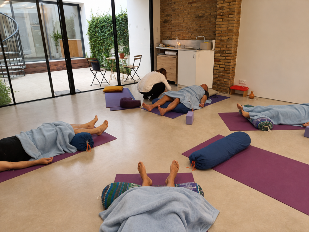 Varias personas tumbadas en esterillas de yoga durante una sesión de acupuntura comunitaria