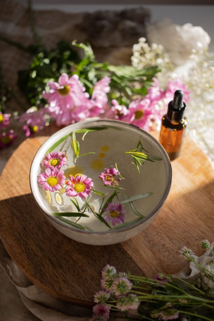 Cuenco con flores flotando junto a una botella para preparar Flores de Bach