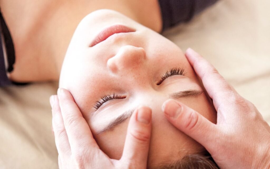 Mans de terapeuta aplicant Reiki sobre la cara d'una dona
