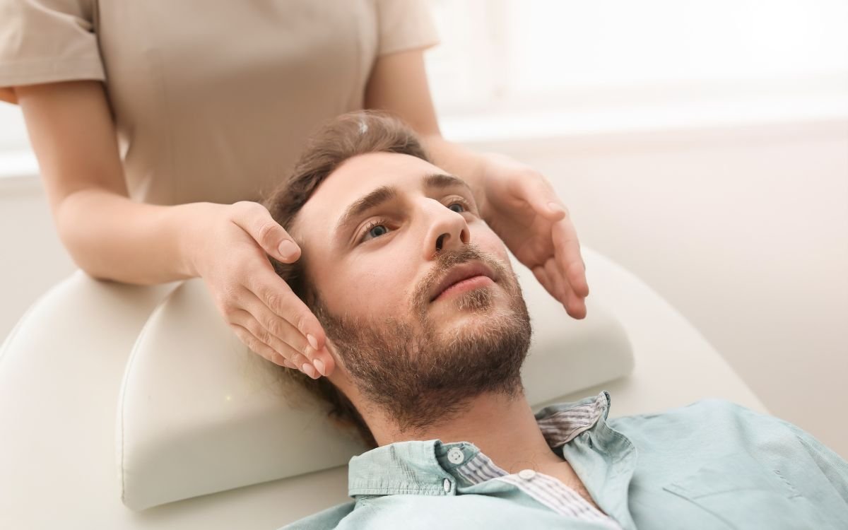 Hombre recibiendo una sesión de Reiki con imposición de manos en la cabeza