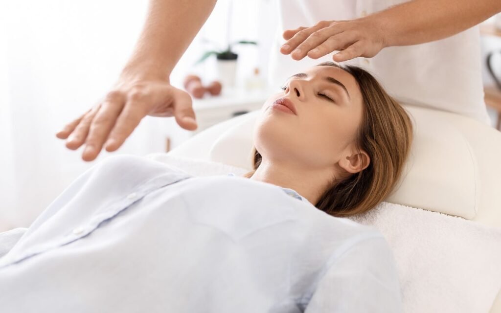 Terapeuta realitzant Reiki a distància a una dona estirada panxa enlaire en una llitera