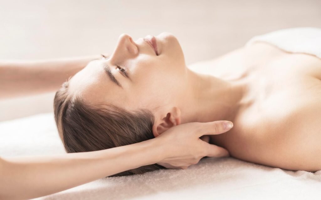 Mujer relajada tumbada boca arriba mientras la terapeuta aplica Reiki en los hombros
